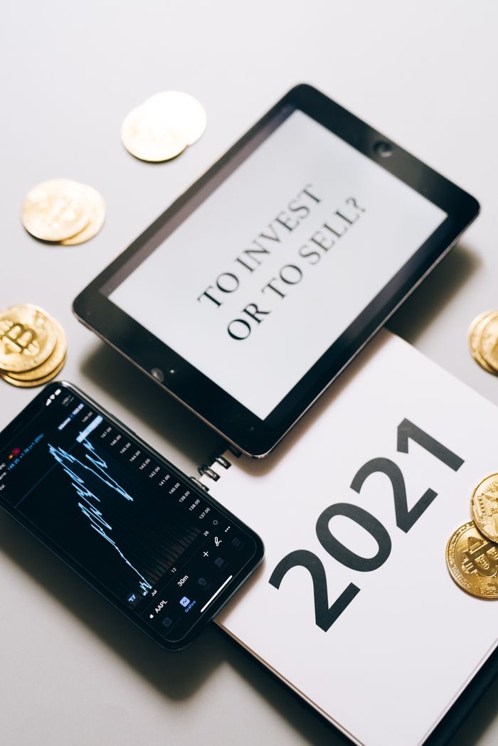 who-we-are Tablet with an investment question surrounded by bitcoins and a 2021 planner. Analyze crypto trends.