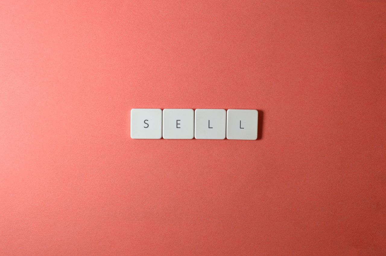 services-03 Close-up of keyboard tiles spelling sell on a red background, minimalist design.